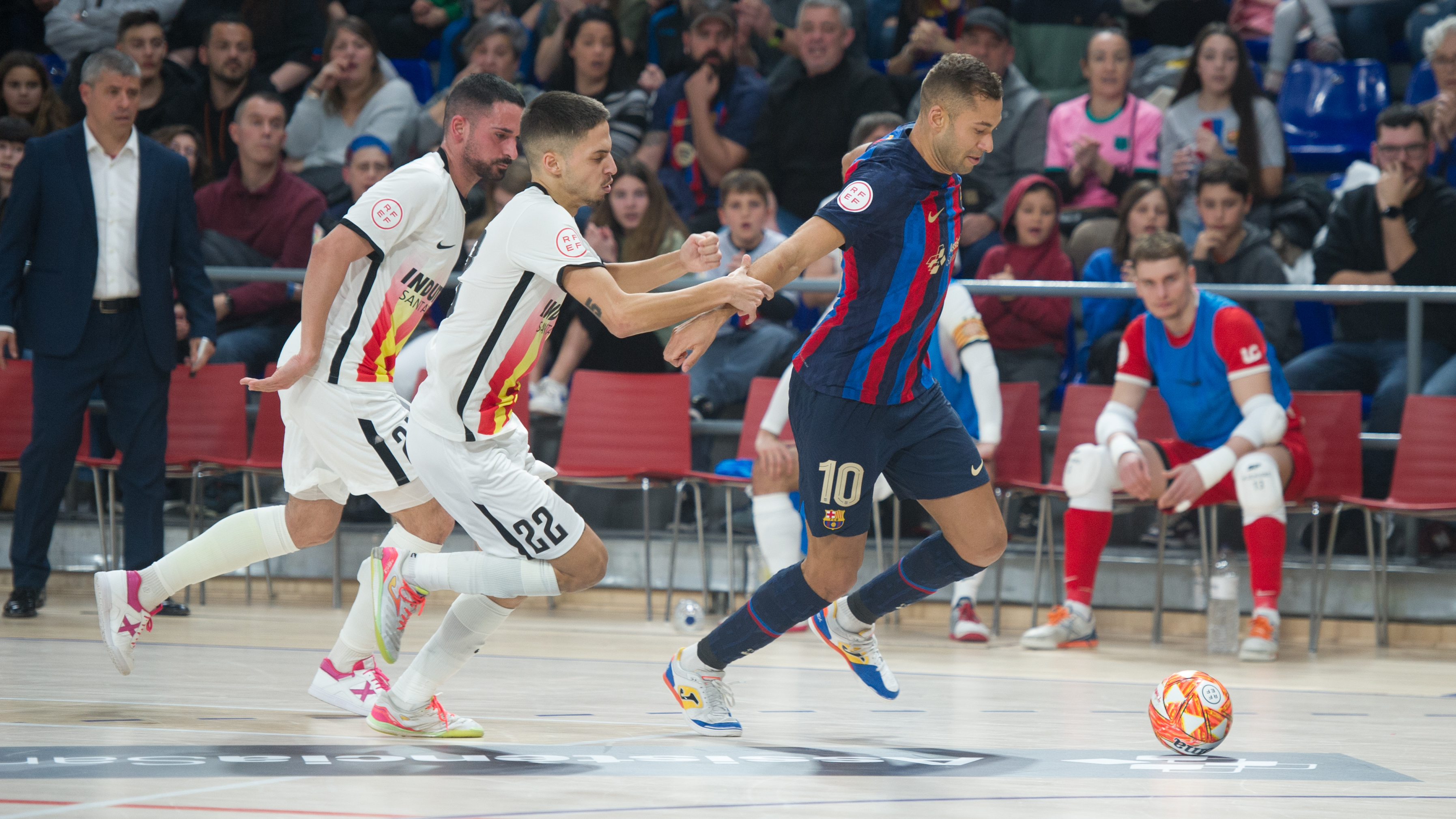 Pito, jugador del Barça, conduce la pelota perseguido por Khalid, de Industrias Santa Coloma