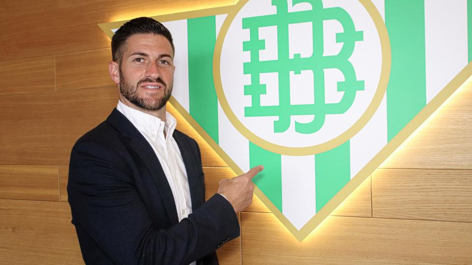 Rubén Cornejo posa junto al escudo del Real Betis Futsal